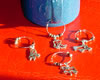 These silver colored cup charms and glass decorations come in the shapes of horses, buffalo, cowboy boots and kokopellis.
