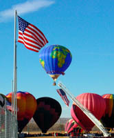 U.S. around the world, a photo graphic of a world shaped balloon surrounded by American Flags in Albuquerque, New Mexico.